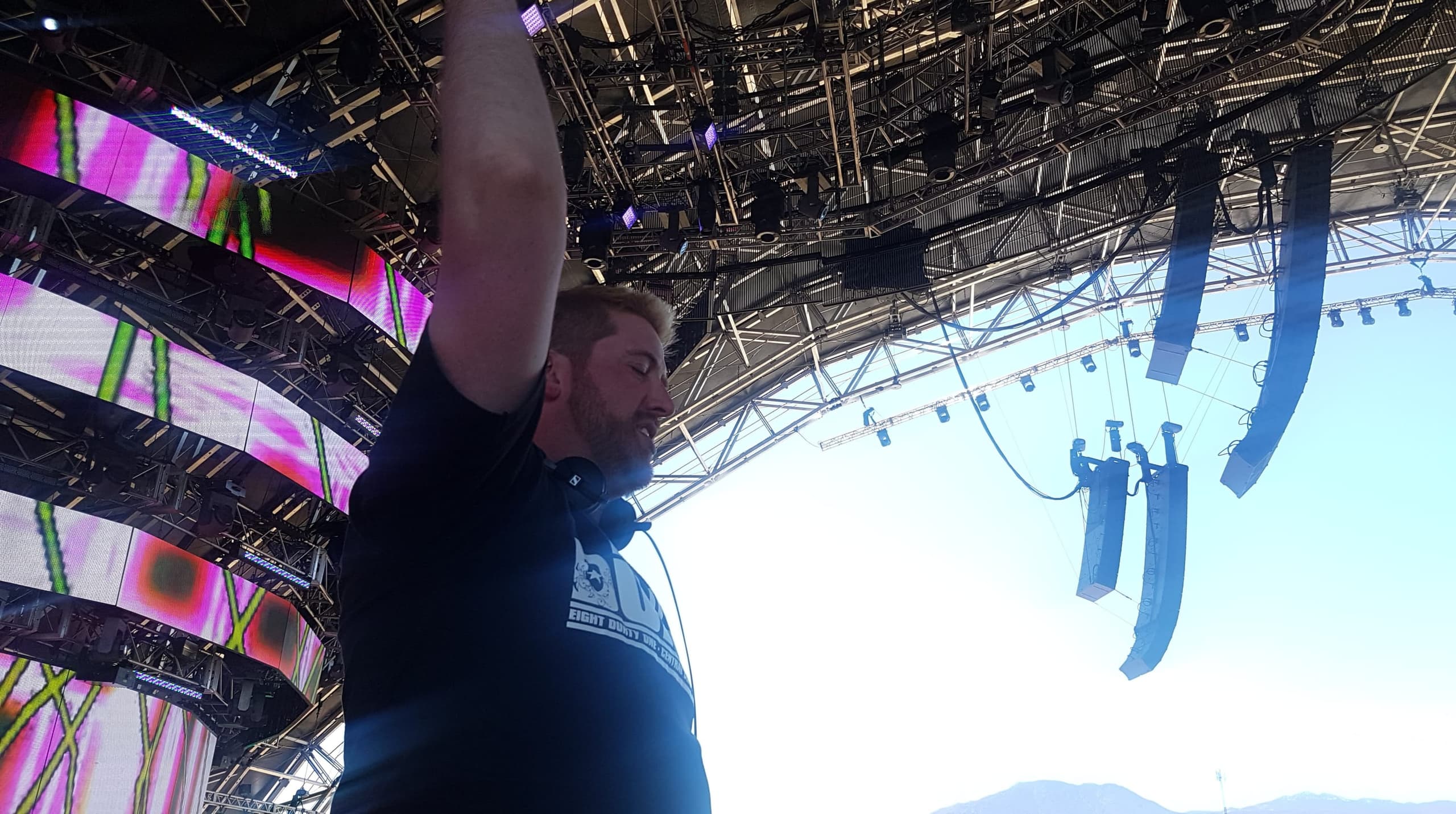 Durty with an arm in the air on the Sahara stage at Coachella, stage rig and line array overhead