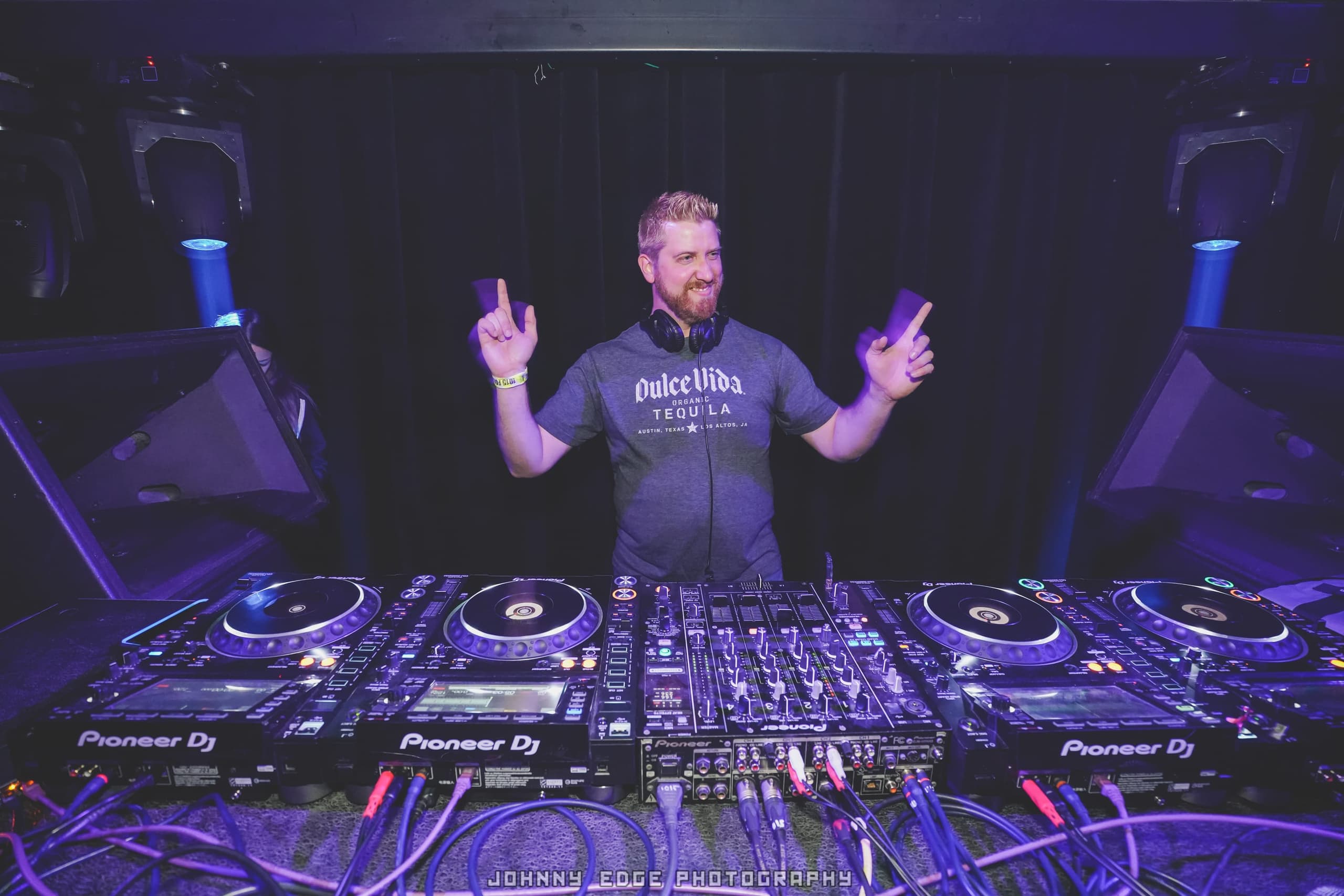 Durty behind a four-deck Pioneer CDJ setup, lit blue and violet